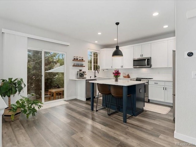 2833 Open Sky Way, Castle Rock, CO 80109 - kitchen with stainless steel appliances, white cabinets, a center island, decorative backsplash, and light countertops