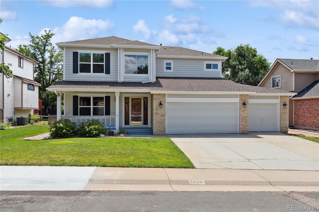 view of property featuring a garage, central air condition unit, a front lawn, and covered porch