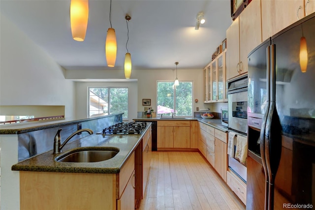 kitchen featuring pendant lighting, black fridge with ice dispenser, sink, and dark stone countertops