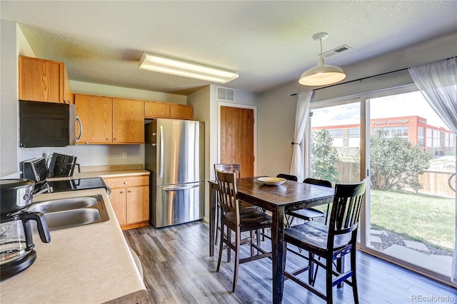 6330 Rockville Dr, Colorado Springs, CO 80923 - kitchen featuring freestanding refrigerator, light countertops, dark wood finished floors, pendant lighting, and a textured ceiling