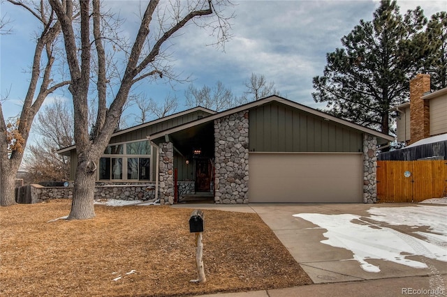 mid-century home with a garage, stone siding, board and batten siding, and concrete driveway