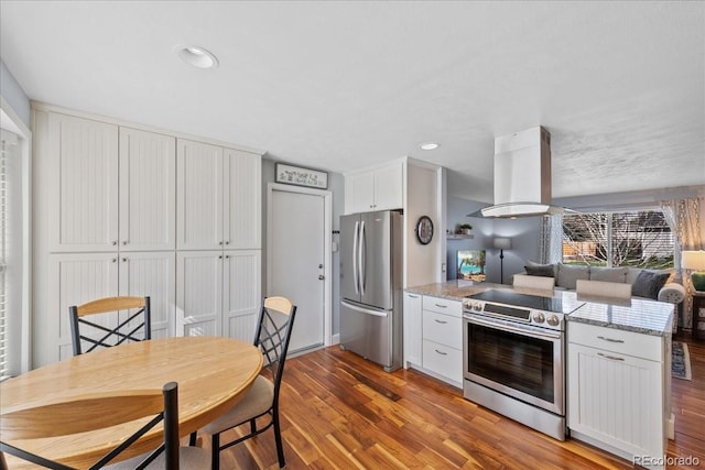 kitchen with a peninsula, open floor plan, light wood-type flooring, white cabinetry, and stainless steel appliances