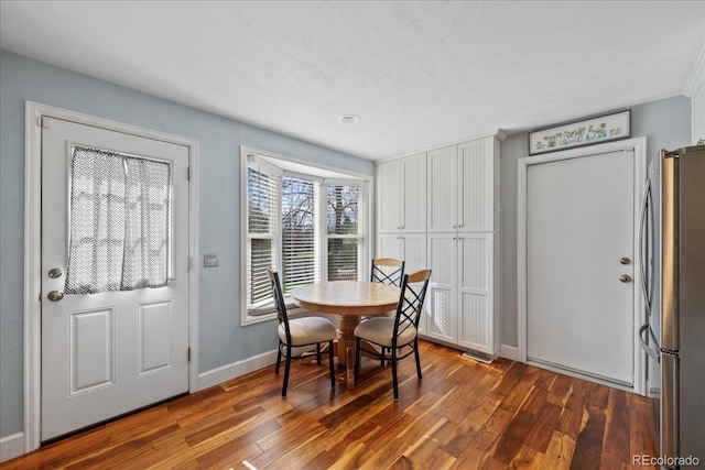 dining space with baseboards and wood finished floors