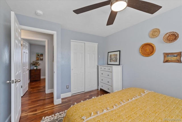 bedroom featuring baseboards, a ceiling fan, a closet, and dark wood-style flooring