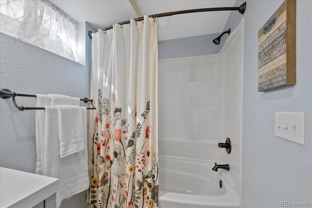 bathroom with a textured wall and shower / bath combination with curtain
