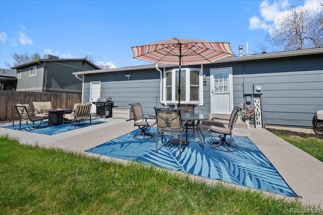 back of property with fence, a patio area, and an outdoor fire pit
