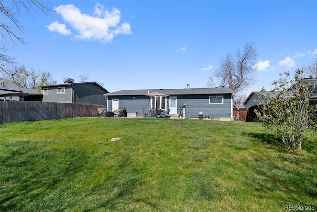 back of house featuring a lawn and fence