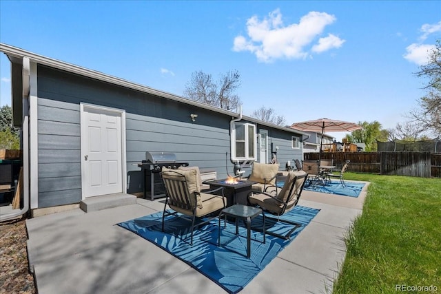back of house featuring a lawn, a patio, fence, and an outdoor fire pit