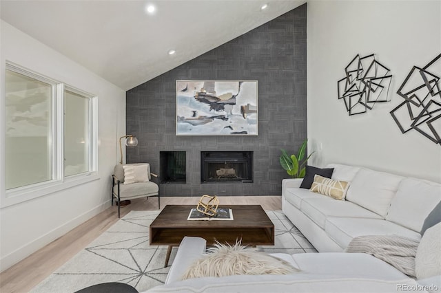 living area with an accent wall, lofted ceiling, baseboards, a fireplace, and recessed lighting