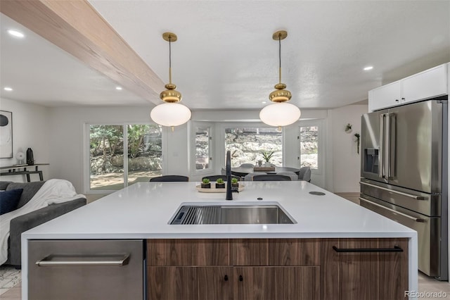 kitchen featuring appliances with stainless steel finishes, open floor plan, a sink, light countertops, and recessed lighting
