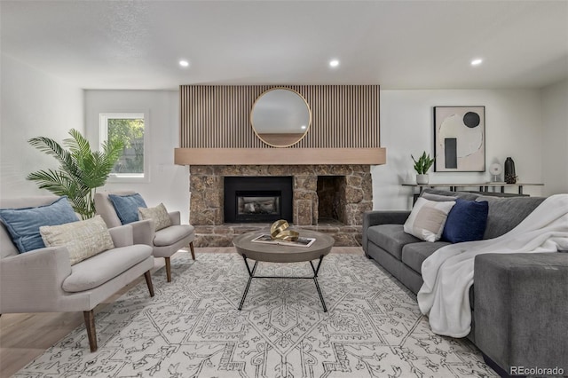 living area with recessed lighting, a stone fireplace, and wood finished floors