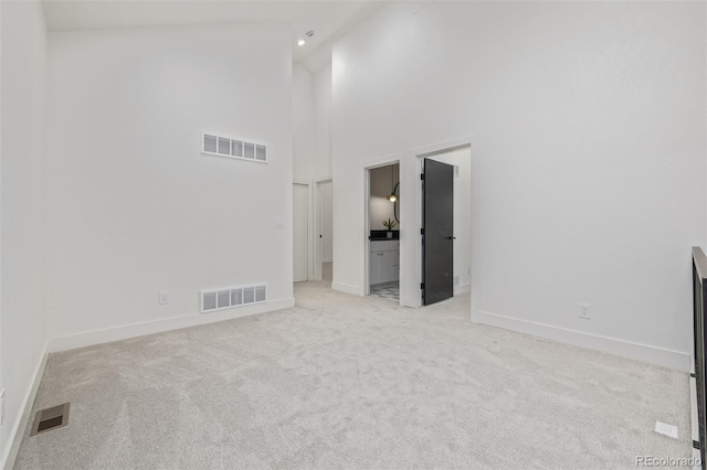 unfurnished room with light colored carpet, baseboards, a high ceiling, and recessed lighting