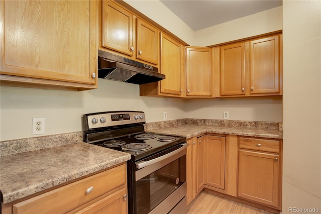 kitchen featuring under cabinet range hood, stainless steel electric range oven, light countertops, and light brown cabinetry