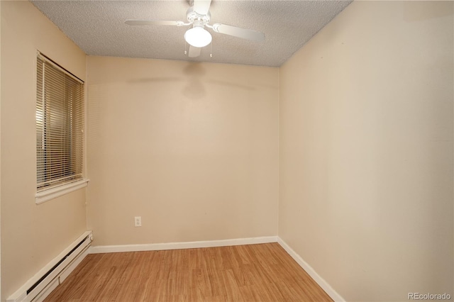 empty room with a textured ceiling, light wood-style floors, baseboards, and a baseboard radiator