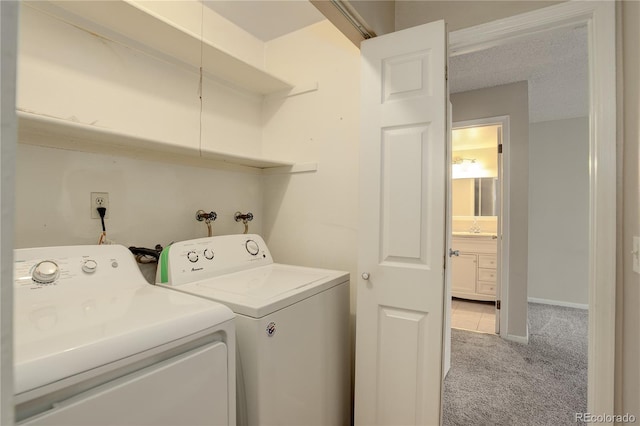 laundry area featuring washer and dryer, a textured ceiling, and light colored carpet