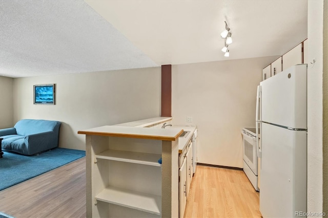 kitchen with white appliances, light hardwood / wood-style flooring, sink, and kitchen peninsula