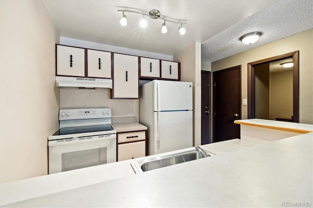 kitchen with sink, white appliances, a textured ceiling, and white cabinets