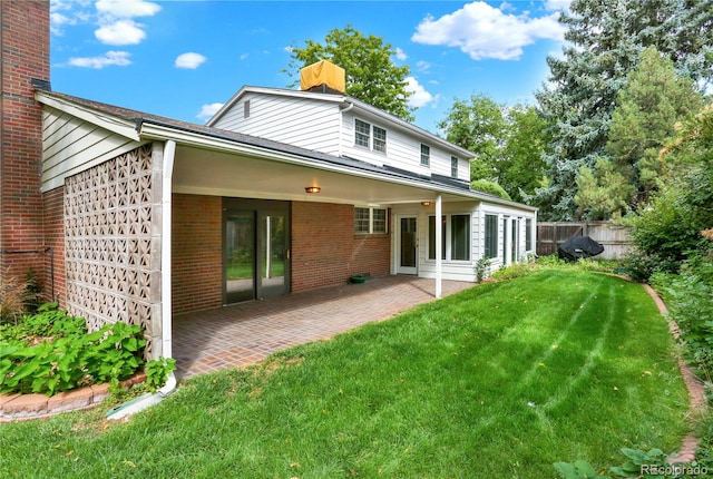 back of property with a yard and a patio area