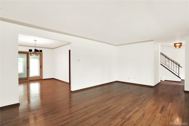 unfurnished room featuring an inviting chandelier, crown molding, and dark wood-type flooring