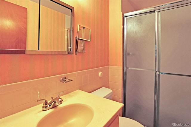 bathroom featuring vanity, tile walls, a shower with shower door, and toilet