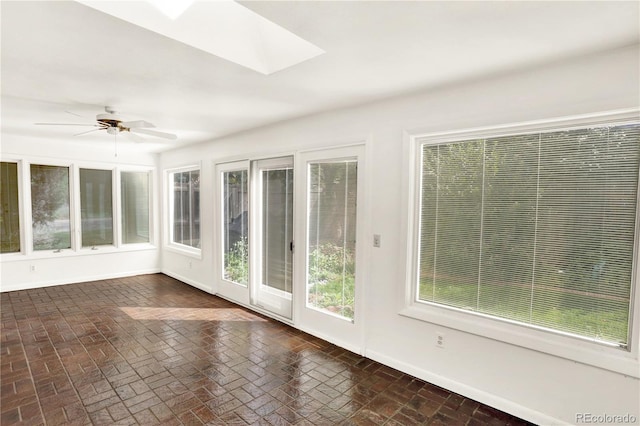 unfurnished sunroom featuring ceiling fan and a skylight