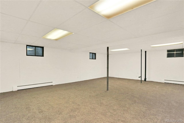 basement featuring a baseboard radiator, a drop ceiling, and carpet flooring