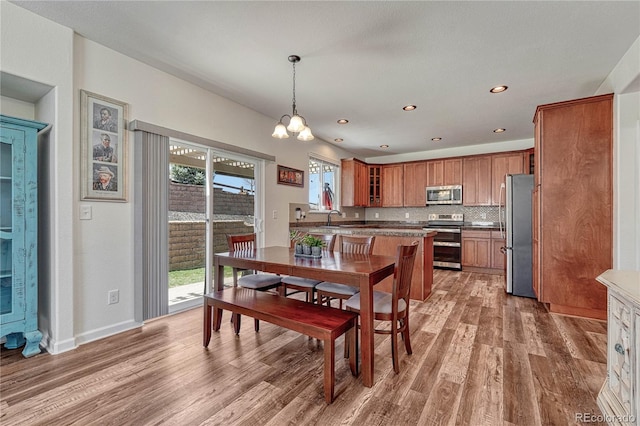 dining space featuring baseboards, light wood-type flooring, a notable chandelier, and recessed lighting