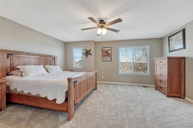 bedroom featuring a textured ceiling, light colored carpet, a ceiling fan, visible vents, and baseboards