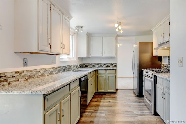 kitchen with black dishwasher, stainless steel range with gas stovetop, light stone countertops, under cabinet range hood, and a sink