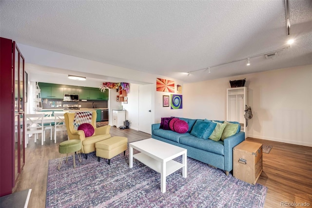 2917 S Locust St, Denver, CO 80222 - living area featuring wood finished floors, a textured ceiling, rail lighting, and baseboards