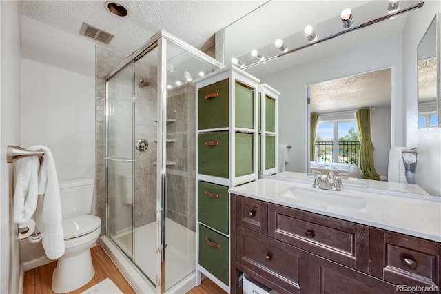 2917 S Locust St, Denver, CO 80222 - ensuite bathroom with a textured ceiling, toilet, a shower stall, vanity, and wood finished floors