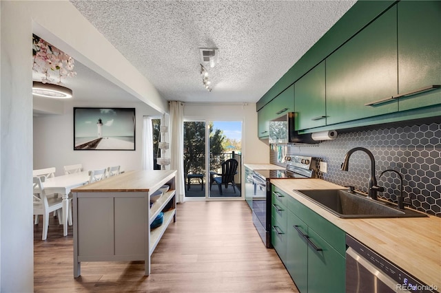 2917 S Locust St, Denver, CO 80222 - kitchen featuring butcher block counters, stainless steel appliances, a sink, green cabinets, and backsplash