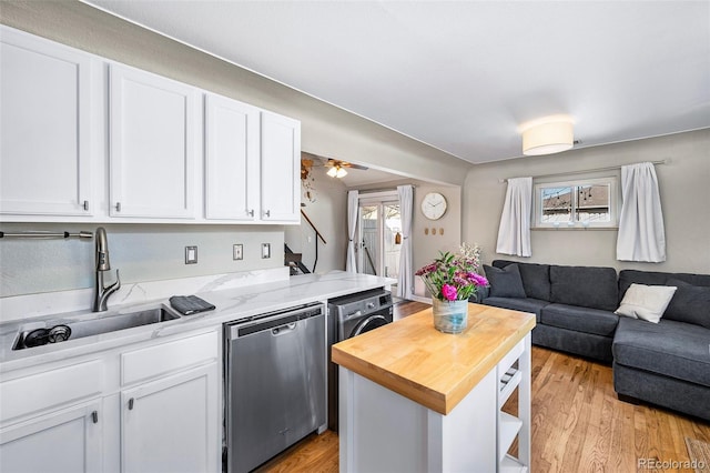 kitchen with dishwasher, butcher block counters, open floor plan, white cabinetry, and a sink