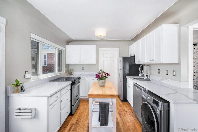 kitchen with stainless steel appliances, washer / clothes dryer, a sink, and white cabinetry