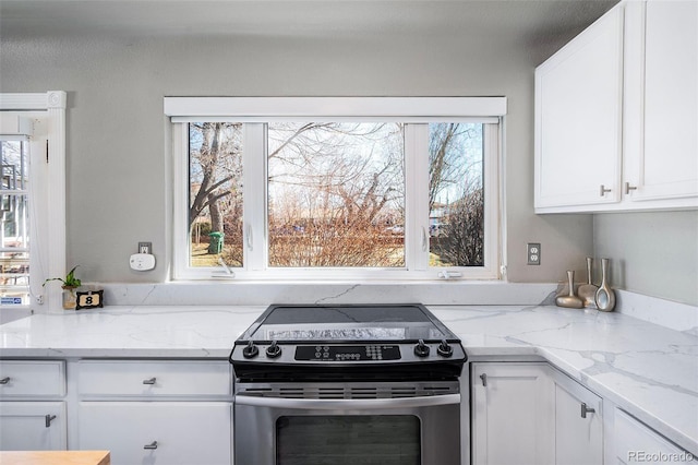 kitchen with light stone counters, white cabinetry, and stainless steel range with electric cooktop