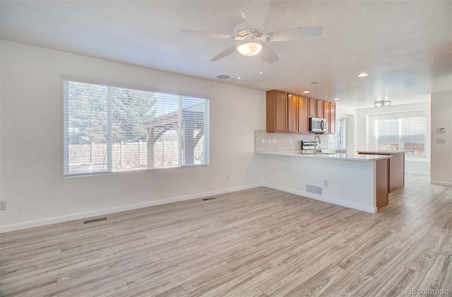 kitchen with sink, tasteful backsplash, light hardwood / wood-style flooring, kitchen peninsula, and ceiling fan