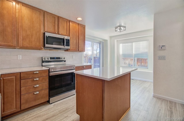 kitchen featuring tasteful backsplash, appliances with stainless steel finishes, a center island, and light wood-type flooring