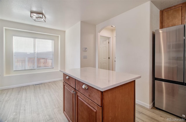 kitchen featuring a center island, stainless steel refrigerator, and light wood-type flooring