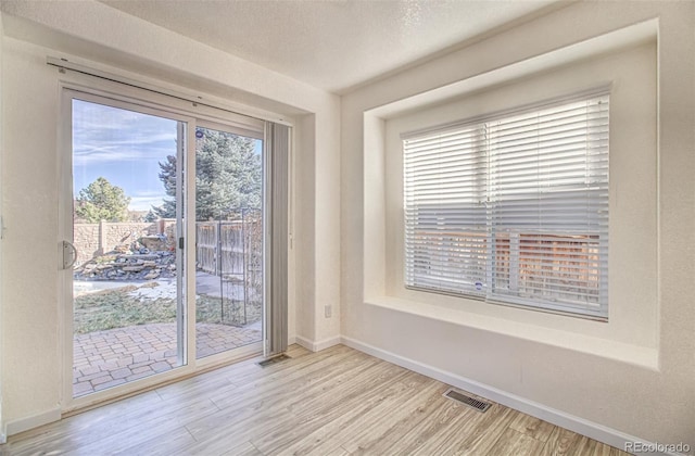 spare room with a textured ceiling and light wood-type flooring