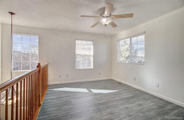 empty room featuring ceiling fan, a healthy amount of sunlight, and dark hardwood / wood-style floors