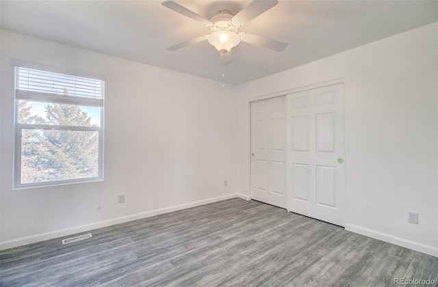 unfurnished bedroom featuring hardwood / wood-style flooring, ceiling fan, and a closet