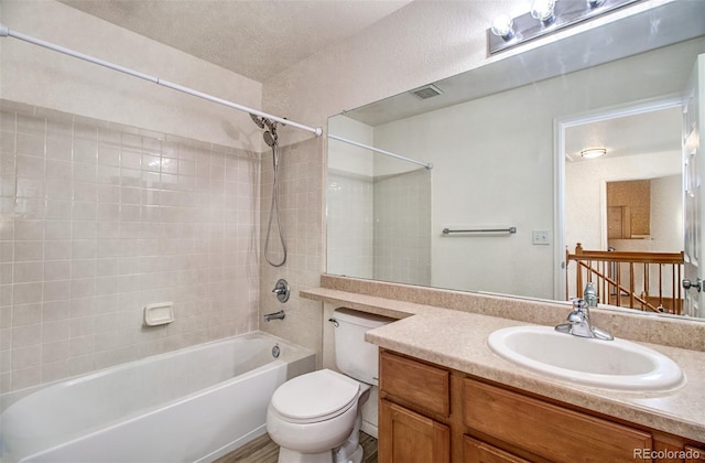 full bathroom with tiled shower / bath, vanity, and toilet