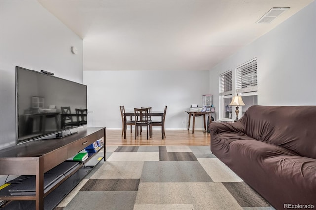 living room with wood finished floors, visible vents, and baseboards