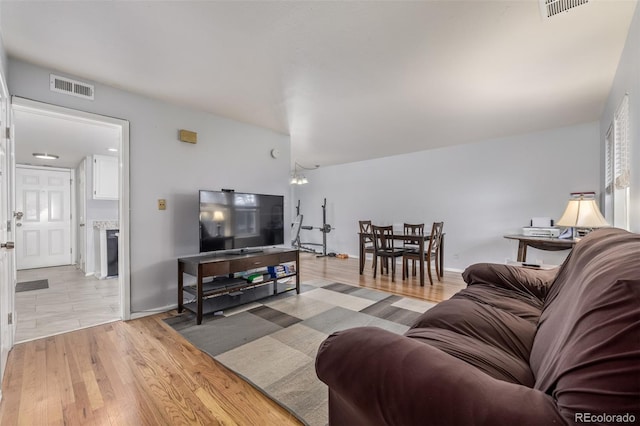 living area with baseboards, visible vents, and light wood-type flooring