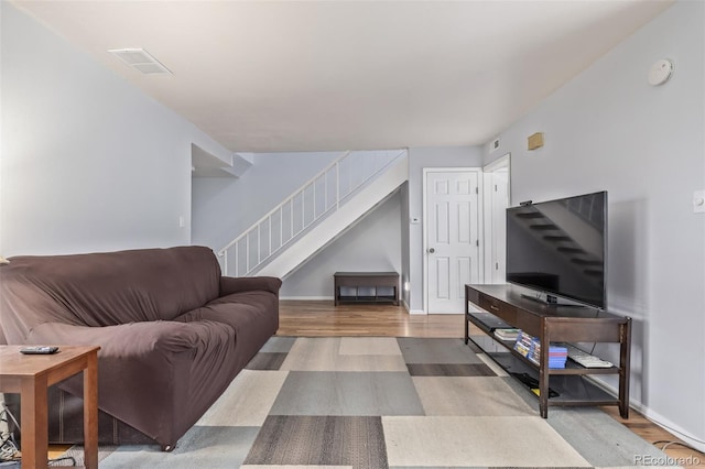 living room featuring visible vents, stairs, baseboards, and wood finished floors