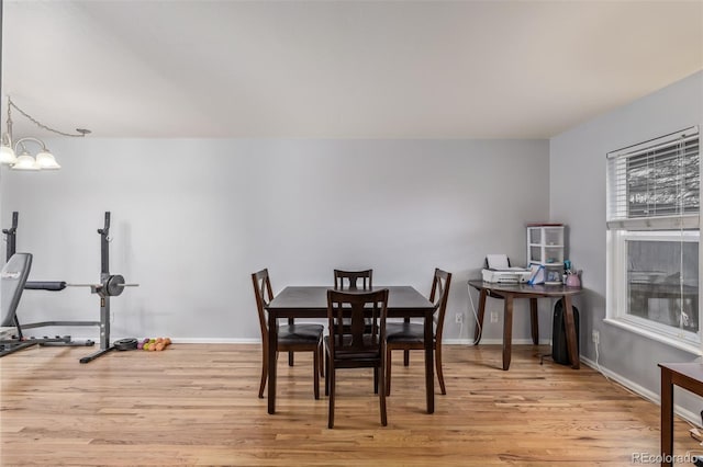 dining space featuring baseboards, light wood-style floors, and an inviting chandelier