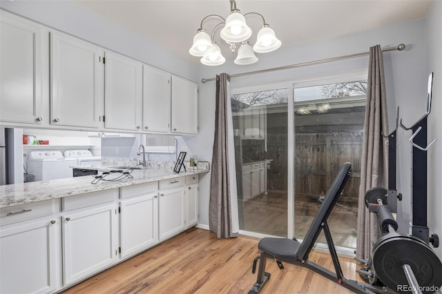 kitchen featuring a sink, light wood-type flooring, white cabinetry, and washer and clothes dryer