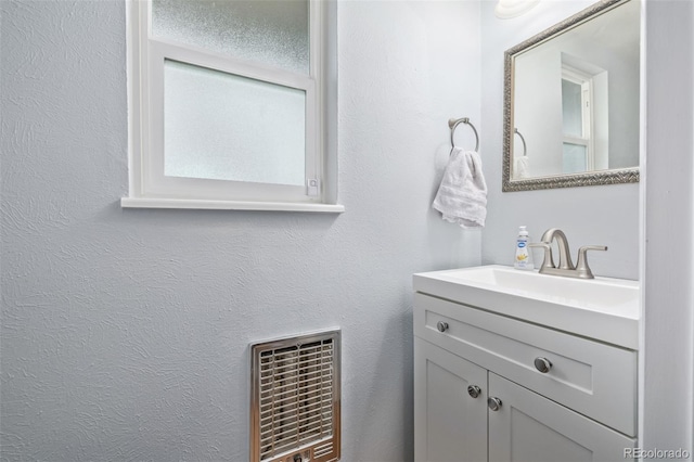 bathroom with visible vents, plenty of natural light, vanity, and a textured wall