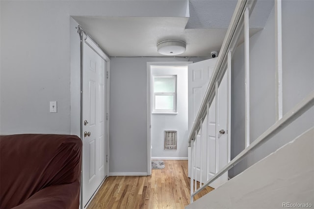 foyer entrance with visible vents, baseboards, stairs, and light wood finished floors