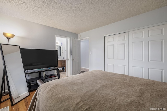 bedroom with a closet, visible vents, a textured ceiling, and wood finished floors